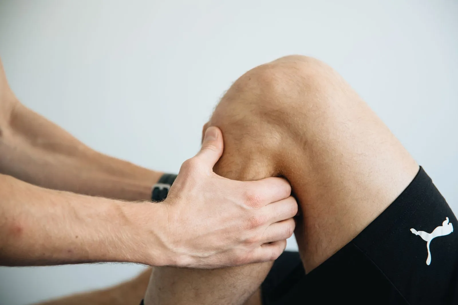 Manos de un fisioterapeuta tratando la rodilla de un paciente
